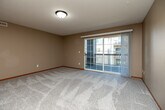 Located at 3205 Samuel Ct SW in Cedar Rapids, Iowa, this single-floor, two-bedroom, two-bathroom residence offers a practical and comfortable layout. The open living area features plush carpeting, neutral beige walls, a textured ceiling, and a sliding glass door that leads to a private balcony, filling the space with natural light. An in-unit washer and dryer are conveniently accessible from the living area. The kitchen is equipped with warm oak cabinetry, ample counter space in an efficient L-shaped configuration, and white appliances including a refrigerator, range, microwave, and dishwasher. Light tile-style flooring runs through the kitchen and entry area. The spacious primary bedroom includes a generous walk-in style closet with built-in shelving and racking, providing excellent storage. The second bedroom features a large window with neighborhood views and soft carpeting. Each bathroom offers clean, functional fixtures — one with a full tub-shower combo and the other with a standalone shower stall, both with tile flooring. A connecting hallway ties all rooms together seamlessly, and two closets throughout the unit ensure ample storage. The overall ambiance is clean, neutral, and move-in ready.