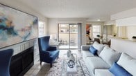 This single-floor residence offers a thoughtfully designed layout that balances comfort and functionality across its key living areas. The living room serves as the heart of the home, featuring light wood-style flooring, a tiled fireplace, and large sliding glass doors that open to a private balcony, filling the space with natural light and outdoor views. A dining area sits adjacent, providing a seamless transition into the galley-style kitchen. The kitchen is well-equipped with stainless steel appliances, including a refrigerator, electric range with over-the-range microwave, and dishwasher, all complemented by white cabinetry, a subway tile backsplash, and a double stainless steel sink. A breakfast bar offers additional seating and connects the kitchen to the dining space. The bedroom is a serene retreat, carpeted for comfort and featuring a ceiling fan, a large sliding glass door to a private balcony, and a spacious sliding-door closet. The bathroom is clean and modern, showcasing a wide vanity with a textured countertop, a large wall mirror with overhead lighting, and white cabinetry. The overall aesthetic throughout the residence is light and neutral, creating a bright and welcoming ambiance.