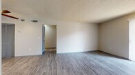 This single-floor unit offers a practical and functional layout designed to maximize everyday comfort. The living area is generously proportioned, featuring gray vinyl plank flooring, neutral-toned walls, and a textured ceiling. A sliding glass door with vertical blinds allows natural light to fill the space while providing access to the outdoors. An entry door opens directly into this open living zone, which flows conveniently toward the kitchen.

The galley-style kitchen is equipped with warm wood cabinetry, light countertops, a double-basin sink, and a full suite of black appliances, including a refrigerator, range, and dishwasher. Vinyl plank flooring continues throughout this area, making for easy maintenance.

The bedrooms are carpeted and feature ceiling fans with light fixtures, offering comfort and airflow. Each room provides ample wall space, and at least one bedroom includes access to a dedicated closet area. Natural light filters in through blinds-covered windows, creating a bright and airy feel.

The bathroom is well-appointed with a wood-toned vanity, light countertop, a large wall mirror, and a full tub-shower combination. Vinyl plank flooring ties the space together cleanly, maintaining a consistent aesthetic throughout the unit.