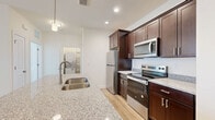 Located at 2950 Ashwood Cir in Harrisburg, PA, this 2-bedroom, 1-bathroom residence offers a thoughtfully designed single-floor layout with contemporary finishes throughout. The open-concept kitchen and living area serves as the heart of the home, where light hardwood-style flooring, crisp white walls, and a ceiling fan create a bright and comfortable atmosphere. A sliding glass door with a transom window above floods the living room with natural light and provides views of the surrounding community.

The kitchen is a standout feature, equipped with rich dark-espresso cabinetry, stainless steel appliances including a refrigerator, electric range, and built-in microwave, and a generous granite-topped island with an undermount sink and pendant lighting overhead. A dedicated closet is conveniently accessible from this central space.

The primary bedroom is generously sized, featuring plush carpet, dual windows that bring in ample natural light, and a ceiling fan for year-round comfort. The second bedroom continues the light hardwood-style flooring and includes a window with neighborhood views. The full bathroom offers a tub-shower combination with brushed nickel fixtures and a window for natural ventilation. The unit also includes in-unit laundry hookups, adding everyday convenience.