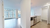 Located in the heart of downtown Montréal on Boulevard René-Lévesque Ouest, this modern 2-bedroom, 1-bathroom unit offers a well-designed layout with clean, contemporary finishes throughout. The open-concept living area is flooded with natural light through expansive floor-to-ceiling windows that frame dynamic city views, complemented by rich hardwood-style flooring. The kitchen features a crisp white design with high-gloss cabinetry, a marble-look tile backsplash, white quartz countertops, stainless steel appliances including a built-in oven, and a peninsula with an undermount sink — ideal for both cooking and entertaining. The primary bedroom is a comfortable size, equipped with a wall-mounted air conditioning unit and access to a dedicated closet with wire shelving. The second bedroom also benefits from large windows offering city views and light tones throughout. The bathroom is elegantly finished with large-format grey stone-look tiles, a soaking tub, a glass-enclosed shower, and recessed lighting. Two closets provide ample storage, and a dedicated laundry area houses a stacked Whirlpool washer and dryer for added convenience.