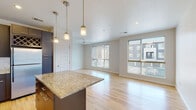 Located at 4780 Willow St in Denver's vibrant Central Park neighborhood, this single-floor residence offers a thoughtfully designed open-concept layout with a clean, contemporary aesthetic. Light-toned hardwood flooring runs throughout the main living areas, reflecting abundant natural light that pours in through large sliding windows in the spacious living room, which is also equipped with a ceiling fan.

The kitchen is a standout feature, anchored by a granite-topped island with pendant lighting overhead. Dark espresso cabinetry extends to the ceiling, complemented by a decorative wine rack, a patterned tile backsplash, stainless steel appliances, and recessed lighting—creating a polished, functional workspace that opens seamlessly to the living area.

The bedroom features plush carpeting, a ceiling fan, and access to a walk-in closet equipped with wire shelving and hanging rods. An en-suite bathroom offers a granite-topped vanity with a dark navy cabinet, tile flooring, and a tub-shower combination with tile surround. The overall ambiance is modern and well-appointed, balancing practical storage solutions with stylish finishes throughout.