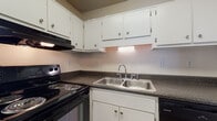 Located at 1025 S Beach St in Daytona Beach, Florida, this single-story unit offers a practical and well-organized layout. The open living area features wood-look hard flooring and a ceiling fan with a light fixture, creating a bright and airy atmosphere. A window dressed with vertical blinds allows natural light to fill the space, while a pass-through connects the living area to the kitchen, enhancing the open feel. The kitchen is equipped with white cabinetry, dark granite-style countertops, a double stainless steel sink, a black electric range with overhead ventilation, and a dishwasher, providing a fully functional cooking space. The bedrooms are carpeted for comfort and feature large windows with vertical blinds that invite natural light. Generous closet space is provided, including a wide louvered bi-fold closet in one bedroom. The bathroom includes a white vanity, wood-look flooring, and a full shower-tub combination with a curtain rod. Throughout the unit, textured ceilings, neutral wall tones, and clean finishes contribute to a cohesive and comfortable living environment.
