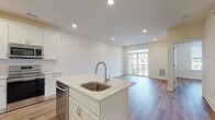 Located at 9172 New Falls Rd in Levittown, PA, this single-floor unit offers a thoughtfully designed open-concept layout with contemporary finishes throughout. The kitchen is a standout feature, equipped with crisp white shaker-style cabinetry, light quartz countertops, and a full suite of stainless steel appliances including a refrigerator, range, microwave, and dishwasher. A central island with a single-basin undermount sink adds both functionality and a natural gathering point that flows seamlessly into the adjoining living area. The living space is bright and inviting, highlighted by warm wood-look flooring that extends throughout the unit, recessed lighting, and a large sliding glass door that opens to a private balcony, allowing abundant natural light and outdoor views. A well-appointed bedroom offers a generous window with exterior views and the same warm flooring, creating a cohesive and comfortable feel. The bathroom features tile flooring, a white vanity with ample storage, and a glass-enclosed shower. Clean neutral walls, white trim, and consistent finishes throughout lend the space a fresh, modern aesthetic that is move-in ready.