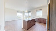 Located at 19888 40th Avenue West in Lynnwood, WA, this thoughtfully designed two-bedroom, two-bathroom residence offers a well-appointed single-floor layout. The open-concept kitchen and living area serves as the heart of the home, featuring a large center island with a quartz countertop, rich wood-toned cabinetry, a white tile backsplash, and a full suite of stainless steel appliances including a refrigerator, range, microwave, and dishwasher. Stylish globe pendant lights hang above the island, complementing the recessed lighting throughout. Light wood-tone flooring flows seamlessly across the entire space, enhancing the bright and airy atmosphere created by an abundance of large windows that frame scenic outdoor views of the surrounding Lynnwood landscape. The generously sized primary bedroom features a walk-in closet with wire shelving and a sliding barn-style door with a frosted glass panel—a distinct design detail. The second bedroom also benefits from expansive windows and ample closet space. Two full bathrooms include a tub-shower combination with dark bronze fixtures. Additional conveniences include an in-unit laundry area and dedicated closet storage, rounding out a functional and modern living space.