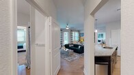 This single-floor residence offers a thoughtfully designed open-concept layout that seamlessly connects the main living areas. The living room is bright and welcoming, featuring hardwood-style flooring, a ceiling fan, and large windows with patio door access that flood the space with natural light and offer outdoor views. The kitchen is well-equipped with dark espresso cabinetry extending to the ceiling, stainless steel appliances including a French door refrigerator, electric range, and built-in microwave, all complemented by granite countertops and a functional island with a sink. A dedicated hallway leads to two comfortable bedrooms, each carpeted and outfitted with ceiling fans and generous windows that bring in natural light. The primary bathroom features a double-sink vanity with dark cabinetry, marble-style countertops, a glass-enclosed walk-in shower, and access to a walk-in closet with wire shelving. The secondary bathroom offers a single-sink vanity with matching dark cabinetry and a tub-shower combination. A dedicated in-unit laundry room houses a full-size Whirlpool washer and dryer set with overhead wire shelving for added storage. Throughout the residence, neutral tones, clean white trim, and consistent finishes create a cohesive and modern aesthetic.
