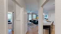 This single-floor residence offers a thoughtfully designed open-concept layout that seamlessly connects the main living areas. The living room is bright and welcoming, featuring hardwood-style flooring, a ceiling fan, and large windows with patio door access that flood the space with natural light and offer outdoor views. The kitchen is well-equipped with dark espresso cabinetry extending to the ceiling, stainless steel appliances including a French door refrigerator, electric range, and built-in microwave, all complemented by granite countertops and a functional island with a sink. A dedicated hallway leads to two comfortable bedrooms, each carpeted and outfitted with ceiling fans and generous windows that bring in natural light. The primary bathroom features a double-sink vanity with dark cabinetry, marble-style countertops, a glass-enclosed walk-in shower, and access to a walk-in closet with wire shelving. The secondary bathroom offers a single-sink vanity with matching dark cabinetry and a tub-shower combination. A dedicated in-unit laundry room houses a full-size Whirlpool washer and dryer set with overhead wire shelving for added storage. Throughout the residence, neutral tones, clean white trim, and consistent finishes create a cohesive and modern aesthetic.
