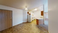 Located at 3550 42nd St S in Fargo, North Dakota, this single-floor unit offers a practical and well-organized layout designed for comfortable everyday living. The kitchen is equipped with warm wood-toned cabinetry, light countertops, a double-basin sink, a dishwasher, and standard appliances including a refrigerator and range. Pendant lighting adds character overhead, while a pass-through window connects the kitchen to the adjacent living area, enhancing the open feel between spaces. The living area is generously sized with neutral carpet, a textured ceiling, baseboard heating, and a wall-mounted air conditioning unit. Sliding glass doors lead to an outdoor patio, allowing for natural light and exterior access. The bedrooms are carpeted and feature windows that bring in natural light, along with baseboard heaters for year-round comfort. One bedroom includes a walk-in closet with dual wire shelving on both sides, offering ample storage. The unit includes two full bathrooms, each with a tub-shower combination, tile flooring, vanity with countertop, and towel bars. Throughout the unit, warm wood trim accents the floors, and the neutral color palette creates a clean, move-in-ready atmosphere.