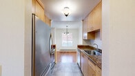 Located at 4816 San Pablo Dam Rd in El Sobrante, CA, this 2-bedroom, 1-bathroom unit offers a well-organized single-floor layout. Rich hardwood flooring flows consistently throughout the living spaces and bedrooms, creating a warm and cohesive aesthetic. The living room is generously sized, featuring a sliding glass door fitted with vertical blinds that invites natural light and provides outdoor access. A wall-mounted heater and baseboard heating units are present throughout the unit. The galley-style kitchen is efficiently designed with warm wood cabinetry, dark granite countertops, tile flooring, stainless steel appliances including a range, microwave, refrigerator, and dishwasher, and a single-basin sink — all illuminated by a central ceiling fixture. Both bedrooms feature hardwood floors, crown molding, textured ceilings, and large built-in wooden storage cabinets that span entire walls, offering substantial closet space. The primary bedroom is spacious and well-lit with a large window. The full bathroom is finished with stone-look tile flooring, a tiled tub-shower surround, a wood vanity with granite countertop, and a mirror. A hallway connects the rooms, completing the functional floor plan.