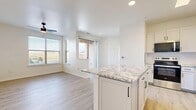 This contemporary apartment showcases a thoughtful design that maximizes space and light. The open floor plan creates a seamless flow between living areas, all adorned with elegant wood-look flooring that adds warmth and durability. Large windows throughout provide abundant natural light and offer picturesque city views, enhancing the sense of spaciousness.

The kitchen is a highlight, boasting sleek white cabinetry, stainless steel appliances, and a generous island with granite countertops. It's perfectly equipped for both everyday meals and entertaining. The bathroom continues the modern aesthetic with a clean, white palette and ample counter space.

Bedrooms are bright and airy, with ceiling fans for comfort and walk-in closets for storage. The apartment also features a dedicated laundry area and additional storage solutions, including a walk-in closet with built-in shelving.

Energy-efficient fixtures, including recessed lighting and modern ceiling fans, complement the overall design. The neutral color scheme provides a blank canvas for personal style, while the quality finishes throughout speak to the property's attention to detail and comfort.