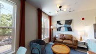 Located at 87 Union St in New Haven, Connecticut, this thoughtfully designed single-floor unit blends contemporary style with functional living. The open-concept layout connects the kitchen, dining, and living areas seamlessly, creating a bright and cohesive flow throughout the space. Light hardwood-style flooring runs through the main living areas, complemented by recessed lighting and natural light from multiple windows dressed with warm rust-colored curtains.

The well-appointed kitchen features sleek white shaker cabinetry extending to the ceiling, grey quartz countertops, stainless steel appliances including a refrigerator, dishwasher, and range with over-the-range microwave, and a single-basin sink. A compact dining area with a marble-top table sits adjacent to the kitchen, bathed in natural light.

The living area is comfortably furnished with a leather loveseat, accent chair, round wooden coffee table, and a bold statement art piece, all anchored by a plush area rug. A modern multi-globe light fixture adds a stylish focal point overhead. The sleeping area is partitioned within the unit, offering a sense of privacy. The bathroom features tile flooring, a tub-shower combination with a curved curtain rod, and matte black fixtures throughout, providing a clean, modern finish.