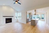 Located at 4617 Chardonnay Lane NE, this thoughtfully designed single-story home offers three bedrooms and two bathrooms across a well-appointed floor plan. The open-concept living and kitchen area is the heart of the home, anchored by vaulted ceilings and light hardwood flooring that flows seamlessly throughout. The living room features a striking fireplace with a dark mantel, flanked by large windows with plantation shutters that flood the space with natural light and offer views of lush greenery outside. A ceiling fan overhead adds a practical finishing touch. The kitchen is a standout, boasting a generous island with a crisp white quartz countertop, sleek gray shaker cabinetry, stainless steel appliances including a French door refrigerator, and a statement stainless steel range hood. Pendant lighting adds warmth and style above the island. Additional windows and sliding glass doors bring in abundant light and provide outdoor access. The bedrooms are carpeted and finished in neutral tones, offering a calm and comfortable retreat, with closets providing convenient storage. The bathrooms are elegantly appointed with large-format tile flooring, gray vanities, and a tub-shower combination with glass enclosure. A wall-mounted mini-split unit ensures efficient climate control in the bedrooms.
