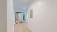 Located on the iconic Wilshire Boulevard in the heart of Los Angeles, this modern one-bedroom, one-bathroom unit offers a thoughtfully designed open-concept layout. The combined kitchen and living area is bathed in natural light from expansive floor-to-ceiling windows that frame urban views of the surrounding cityscape. Light wood flooring flows throughout, complementing the crisp white walls and creating a clean, contemporary aesthetic.

The kitchen is well-appointed with sleek gray cabinetry featuring matte black hardware, white quartz countertops, and a striking teal geometric tile backsplash that adds a vibrant pop of color. Stainless steel appliances — including a full-size refrigerator, range with over-the-range microwave, and dishwasher — complete the functional and stylish cooking space.

The bedroom features the same light wood flooring and neutral white walls, offering a calm and minimalist retreat. The bathroom is finished with earthy brown stone-look tile flooring, a tub-shower combination with floor-to-ceiling gray subway tile surround, and a modern white vanity with a large mirror and ample storage. Overall, the unit presents a cohesive modern design with quality finishes, abundant natural light, and a prime urban location.