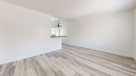 This single-story, one-bedroom, one-bathroom unit at 630 N Cerritos Ave in Azusa, California, offers a clean and functional layout finished with consistent light wood-style luxury vinyl flooring throughout. The open living and dining area is straightforward in scale, featuring white walls, a textured ceiling, and a ceiling fan, creating a bright and neutral atmosphere. A wall-mounted heater provides direct climate control to the main living space.

The kitchen is separated from the living area by a half-wall breakfast bar with a dark countertop, offering a natural division between spaces while maintaining an open feel. The kitchen is equipped with white shaker-style cabinetry extending to the upper walls, dark stone-look countertops, an undermount sink with a modern faucet, and a black refrigerator. Windows with horizontal blinds bring in natural light.

The bedroom is comfortably sized, featuring a ceiling fan, a window with an outdoor view, and a full-width sliding-door closet for practical storage. The bathroom includes a tiled tub-and-shower combination with chrome fixtures, a white vanity with under-cabinet storage, a wall mirror, and a small window for ventilation. A hallway connects the main living areas efficiently, completing this well-maintained, move-in-ready unit.