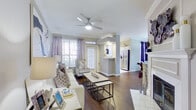 This single-floor residence offers a thoughtfully designed layout that balances comfort and functionality. The living room serves as the heart of the home, featuring rich hardwood flooring, crown molding, a ceiling fan, and generous natural light streaming through large windows dressed with soft lavender drapes. A fireplace adds a classic focal point to the space, while an open sightline connects the room to the rest of the home.

The kitchen is outfitted with white cabinetry, a full suite of stainless steel appliances including a refrigerator, range, microwave, and dishwasher, and light tile flooring. A pass-through opening maintains visual connectivity to the main living area. Adjacent to the living room, the formal dining area features dark hardwood floors, a pendant light fixture, and ample space for entertaining.

Two well-sized bedrooms provide comfortable retreats, each with plush carpeting, crown molding, ceiling fans, and natural light from large windows with blinds. The primary bathroom is elongated and features a dual-sink vanity, large tile flooring, and a private water closet. The secondary bathroom includes a tub-shower combination with sliding glass doors and tile flooring, maintaining a clean, bright aesthetic throughout.