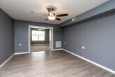 This single-floor, 2-bedroom, 1-bathroom residence in West Burlington, Iowa offers a well-organized and functional layout with a consistent, modern aesthetic throughout. Cool-toned blue-gray walls paired with light wood-look luxury vinyl plank flooring create a clean, cohesive look across the main living areas.

The combined kitchen and living room serves as the heart of the home, offering an open, efficient layout. The kitchen is equipped with dark espresso-toned cabinetry, light countertops, and a full suite of stainless steel appliances including a refrigerator, dishwasher, and electric range. Ample cabinet storage and a dedicated pantry door add to the kitchen's practicality.

Both bedrooms feature plush carpeting, ceiling fans with light fixtures, and windows that allow natural light and outdoor views. The spacious primary bedroom includes a generously sized closet, while the second bedroom offers comfortable proportions with easy access to the main hallway. Two closets throughout the unit provide additional storage.

The bathroom is designed with accessibility in mind, featuring a roll-in style walk-in shower equipped with grab bars, a handheld showerhead, and a low-threshold base. The unit also includes a dedicated laundry area and a utility room, rounding out a thoughtfully designed and fully equipped living space.
