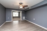 This single-floor, 2-bedroom, 1-bathroom residence in West Burlington, Iowa offers a well-organized and functional layout with a consistent, modern aesthetic throughout. Cool-toned blue-gray walls paired with light wood-look luxury vinyl plank flooring create a clean, cohesive look across the main living areas.

The combined kitchen and living room serves as the heart of the home, offering an open, efficient layout. The kitchen is equipped with dark espresso-toned cabinetry, light countertops, and a full suite of stainless steel appliances including a refrigerator, dishwasher, and electric range. Ample cabinet storage and a dedicated pantry door add to the kitchen's practicality.

Both bedrooms feature plush carpeting, ceiling fans with light fixtures, and windows that allow natural light and outdoor views. The spacious primary bedroom includes a generously sized closet, while the second bedroom offers comfortable proportions with easy access to the main hallway. Two closets throughout the unit provide additional storage.

The bathroom is designed with accessibility in mind, featuring a roll-in style walk-in shower equipped with grab bars, a handheld showerhead, and a low-threshold base. The unit also includes a dedicated laundry area and a utility room, rounding out a thoughtfully designed and fully equipped living space.