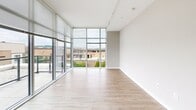 Located at 2827 Telek Pl in Alexandria, VA, this 2-bedroom, 1-bathroom residence offers a well-designed layout across a single floor. The open-concept living room and kitchen area is a standout feature, boasting dramatic floor-to-ceiling glass windows that flood the space with natural light and frame views of the surrounding Alexandria cityscape and greenery below. Light wood-style flooring flows throughout the main living area, enhancing the bright, airy ambiance.

The kitchen is appointed with dark wood-grain cabinetry, a subtle tile backsplash, white quartz countertops, and a full suite of stainless steel appliances including a refrigerator, range, built-in microwave, and dishwasher. Both bedrooms are carpeted for comfort, with the primary bedroom featuring its own floor-to-ceiling window with outdoor views and access to a spacious walk-in closet outfitted with wire shelving systems. The second bedroom is well-proportioned with neutral tones and plush carpet.

The bathroom is finished with dark wood vanity cabinetry, white quartz countertops, an undermount sink, and a large mirror with contemporary lighting. Clean, neutral walls throughout the unit complement the modern finishes, creating a cohesive and polished living environment.