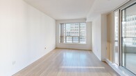 This efficiently designed one-bedroom, one-bathroom unit offers a thoughtful layout across a single floor, making excellent use of every square foot. The open-concept living and kitchen area serves as the heart of the home, bathed in natural light from large floor-to-ceiling windows and a sliding glass door that opens onto a private balcony with urban cityscape views. Light hardwood flooring runs throughout the main living area, adding warmth and continuity to the space.

The kitchen features light maple cabinetry, stainless steel appliances including a refrigerator, electric range, and built-in microwave, complemented by a granite countertop peninsula that doubles as a breakfast bar. Track lighting overhead ensures the kitchen is well-lit and functional.

The hallway connects the main living area to the private bedroom and bathroom, and is lined with mirrored sliding closet doors that enhance the sense of openness. The bedroom is carpeted, bright, and includes a large sliding door closet and access to the balcony with city views.

The full bathroom is finished with tile surrounds, a soaker tub and shower combination, a vanity with integrated storage, and a mirrored medicine cabinet. A dedicated laundry closet with a stacked washer and dryer unit rounds out this practical and complete urban residence.