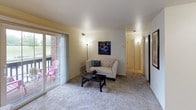 This single-floor residence offers a thoughtfully arranged layout across several well-defined spaces. The living room serves as the heart of the unit, featuring plush carpeting and an abundance of natural light streaming through large sliding glass doors that open onto a private balcony. The outdoor access adds a welcoming sense of openness, making the living area feel bright and airy.

The kitchen is efficiently designed with light wood cabinetry, ample upper and lower storage, a coil-top electric range, a built-in dishwasher, and continuous countertop workspace. Tile flooring grounds the space practically.

Both bedrooms are carpeted and comfortably proportioned, each adorned with distinctive metal wall art as a focal point. One bedroom includes a window that introduces natural light, while the other provides direct hallway access. Both rooms offer a calm, restful atmosphere suited for relaxation or use as a workspace.

The bathroom features a light wood vanity with under-sink storage, a well-lit mirror with overhead Hollywood-style lighting, tile flooring, and clean, neutral finishes throughout. The overall ambiance of the unit is calm and functional, with consistent warm tones, carpeted living spaces, and practical finishes that create a cohesive, livable environment.