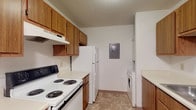 Located at 2960 Abbots Cove Blvd in Columbus, Ohio, this single-floor unit offers a practical and comfortable layout across several well-defined living spaces. The galley-style kitchen is equipped with warm wood cabinetry, a coil-burner electric range, a full-size refrigerator, a dishwasher, and light-toned countertops over tile flooring. A notable feature is the in-unit washer hookup conveniently tucked into the kitchen area, alongside an accessible electrical panel. The open living and dining area transitions seamlessly from the kitchen, featuring neutral carpet, a ceiling fan with light fixture, and baseboard heating. The layout provides a generous, open feel throughout the common areas. The bedrooms are carpeted and well-sized, each outfitted with ceiling fans, baseboard heating, and windows that bring in natural light with views of surrounding greenery. One bedroom includes a dedicated closet with sliding doors, while another features two separate doorways providing flexible access. The full bathroom is clean and straightforward, featuring a soaking tub with shower, tile flooring, and a vanity with storage. Throughout the unit, textured ceilings, neutral wall tones, and wood-trimmed doors contribute to a consistent, practical aesthetic.