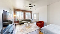 Located at 1775 N Orange Dr in the heart of Hollywood, Los Angeles, this 1-bedroom, 1-bathroom unit blends historic character with modern updates across a thoughtfully designed single floor. The living room serves as the centerpiece of the space, showcasing a striking exposed brick accent wall framed by large arched windows that flood the room with natural light and offer views of the surrounding cityscape. Warm hardwood flooring runs throughout, complemented by a ceiling fan overhead. The kitchen is efficiently laid out with white cabinetry, dark countertops, stainless steel appliances including a full-size refrigerator and gas range, and a window-facing dining nook that adds a bright, airy feel. The bedroom features a recessed nook framing the sleeping area, crisp white walls, and an elegant arched doorway that adds architectural interest. The bathroom is clean and bright, with white walls, hardwood-style flooring, and a window that brings in natural light. A connecting hallway ties the rooms together smoothly. Throughout the unit, the combination of exposed brick, arched architectural details, and updated finishes creates a space that is both characterful and functional — ideal for those seeking a distinctive home in a prime Los Angeles location.