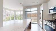Located in Chicago's vibrant Logan Square neighborhood, this modern 4-bedroom, 2-bathroom home offers a well-designed single-floor layout with contemporary finishes and abundant natural light. The open-concept kitchen is a standout feature, boasting an expansive marble-look island with waterfall edges, sleek white cabinetry, stainless steel appliances, and a striking linear pendant light. Floor-to-ceiling windows and a sliding glass door connect the kitchen to the living area and provide views of the surrounding neighborhood. The living room is bright and open, benefiting from the same wall of windows that flood the space with daylight. The four bedrooms feature light hardwood-style flooring and neutral toned walls; several rooms include oversized windows with views of mature trees and the Chicago cityscape. The spacious primary bedroom includes a well-appointed walk-in closet with built-in shelving and hanging rods on both sides. Both bathrooms are finished with large-format marble-look tile flooring and a clean, modern aesthetic, including a soaking tub with a bold striped tile surround. Two closets add convenient storage throughout the home. Light wood-style flooring runs consistently across all living areas, tying the home's modern design together cohesively.