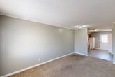Located at 4424 Torrance Dr NW in Huntsville, Alabama, this single-level, 2-bedroom, 1-bathroom home offers a straightforward and functional layout ideal for comfortable everyday living. The living room is a generously sized, open space featuring soft neutral-toned carpet, light gray walls, crown molding, and a textured ceiling — creating a clean, understated aesthetic. The room flows directly into the kitchen, which is equipped with warm honey-oak cabinetry, light granite-style countertops, a double basin sink, white appliances including a range, dishwasher, and refrigerator, and durable wood-look vinyl flooring. The two bedrooms are carpeted and finished with the same neutral gray palette, each offering a calm and restful environment. The primary bedroom includes a window for natural light and an interior door leading to the hallway. The second bedroom also features a window and ample floor space. The single full bathroom is well-appointed with a tub/shower combination, a vanity with a marble-style countertop, warm wood cabinetry, and wood-look vinyl flooring. A central hallway connects all rooms, contributing to an efficient and cohesive floor plan throughout the home.