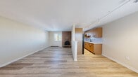 Located at 4701 E Mississippi Ave in Glendale, CO, this two-bedroom, one-bathroom residence offers a well-organized single-floor layout with a thoughtful mix of finishes throughout. The open living and dining area is anchored by a striking full-brick wood-burning fireplace, creating a warm focal point for the space. Light hardwood-style flooring runs throughout the main living areas, complemented by natural light from multiple windows fitted with blinds. The kitchen is efficiently designed with warm wood cabinetry, white quartz countertops, a chevron-pattern tile backsplash, a black matte faucet, and stainless steel appliances. Track lighting illuminates the kitchen, adding a modern touch. Both bedrooms feature plush carpeting and windows that bring in natural light and outdoor views. The primary bedroom includes a large sliding-door closet, providing ample storage. A second closet is also available within the unit for additional storage needs. The hallway connects the living spaces to the bedrooms and bathroom in a straightforward, functional layout. Baseboard heating is present throughout, and a wall-unit air conditioner ensures year-round comfort. The overall aesthetic is clean and contemporary with classic residential character.