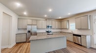 Located at 1510 Sta Blf Dr in Lawrenceville, GA, this two-story home offers four bedrooms and three bathrooms across a well-designed layout spread over two floors. The main level opens through a hallway adorned with classic wainscoting panels and hardwood-style flooring that flows throughout. The open dining and living area is bathed in natural light from large windows and features an elegant chandelier, creating a bright and welcoming atmosphere. The kitchen is a standout, equipped with granite countertops, a central island, gray shaker-style cabinetry, a subway tile backsplash, and a full suite of stainless steel appliances, including a refrigerator, range, microwave, and dishwasher. Upstairs, the generously sized primary bedroom impresses with a tray ceiling, ceiling fan, plush carpeting, and multiple windows. It is complemented by a large walk-in closet with wire shelving and ample storage. Three additional bedrooms provide flexible space for various needs, and a dedicated laundry room with washer/dryer connections adds everyday convenience. Three full bathrooms serve the home throughout. Neutral tones and clean finishes carry a consistent, move-in-ready aesthetic from room to room.