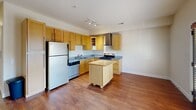 Located at 316 King St in Greensboro, NC, this one-bedroom, one-bathroom residence offers a thoughtfully designed single-floor layout. The kitchen is a standout feature, showcasing warm honey-toned wood cabinetry, granite countertops, and stainless steel appliances including a refrigerator, dishwasher, and electric range. A freestanding butcher block island provides additional prep space and adds a functional centerpiece to the room, while track lighting overhead and rich hardwood flooring complete the polished look. The open layout allows the kitchen to connect seamlessly to the living area, enhancing the sense of space throughout. The bedroom offers a comfortable retreat with plush wall-to-wall carpeting, a ceiling fan with light fixture, and a generous built-in closet with wire shelving for ample storage. Neutral, warm-toned walls create a calm and inviting ambiance throughout. The bathroom features tile flooring, a granite-topped vanity with wood cabinetry, and a shower-tub combination, maintaining the consistent, quality finishes found throughout the home. Dark wood panel doors add a classic touch that ties the interior design together cohesively.