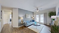 This single-floor residence offers a thoughtfully designed layout that balances comfort and style. The living room serves as the heart of the home, featuring rich hardwood-style flooring, a ceiling fan with integrated lighting, and large windows dressed with grommet-top curtains that invite abundant natural light. A bold grey accent wall adds depth and character to the space. The living area flows seamlessly into a dedicated dining nook, which accommodates a round table set beneath tasteful wall art and a decorative mirror, making it an ideal space for intimate gatherings. The galley-style kitchen is equipped with dark espresso cabinetry, light granite countertops, and black appliances, including a refrigerator and dishwasher, all set atop wood-look flooring. Both bedrooms are carpeted for comfort and feature ceiling fans and windows with views to the outdoors. The primary bedroom includes an en-suite bathroom with a walk-in closet, a tub-shower combination with tiled surround, a dark vanity, and wood-look flooring. The second full bathroom mirrors this design with similar finishes. Throughout the residence, a cohesive blue and neutral color palette ties each space together, creating a calm and welcoming ambiance.