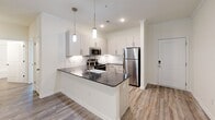 Located in Louisville, Tennessee, this well-appointed 2-bedroom, 2-bathroom single-floor residence offers a thoughtfully designed layout with modern finishes throughout. The open-concept kitchen and living area serves as the heart of the home, featuring light wood-style flooring, crown molding, and recessed lighting. The kitchen is outfitted with crisp white cabinetry, a classic subway tile backsplash, dark granite countertops, a farmhouse sink, and a full suite of stainless steel appliances including a refrigerator, range, microwave, and dishwasher. Stylish pendant lights hang over the peninsula, which flows seamlessly into a bright, open living area with a glass-panel door providing natural light and outdoor views. Both bedrooms are carpeted and feature ceiling fans, natural light from multiple windows, and generous closet space — the primary bedroom includes a spacious layout with multiple closets. The bathrooms offer clean, functional finishes with wood-look flooring. Five closets throughout the home provide abundant storage, complemented by a dedicated laundry area. The neutral color palette and modern design elements create a clean, move-in-ready atmosphere throughout the entire residence.