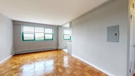 This well-appointed one-bedroom, one-bathroom unit at 12 Marshall St in Irvington, NJ offers a thoughtfully arranged layout across a single floor. The living area is bright and open, showcasing beautifully polished parquet wood flooring in a classic block pattern throughout, complemented by soft gray walls and clean white trim. Multiple windows with green-framed accents invite generous natural light and offer outdoor views, creating an airy and welcoming ambiance. Baseboard heating runs along the perimeter, ensuring comfort year-round.

The kitchen features contemporary wood-tone cabinetry with brushed nickel hardware, crisp white countertops, a stainless steel sink, and a stainless gas range with overhead microwave — functional and stylish in equal measure. The spacious bedroom continues the parquet flooring and includes dual sliding-door closets, providing ample storage. A dedicated window brings in natural light and outdoor views.

The bathroom is notably refined, with marble-style wall tiles lining a full tub and shower combination enclosed by sleek sliding glass doors, paired with a clean white basin vanity for a polished, modern finish. A hallway connects the rooms efficiently, completing this compact yet well-designed home.
