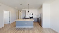 Located at 6271 Riverview Rd SE in Mableton, Georgia, this single-story residence offers a thoughtfully designed layout with contemporary finishes throughout. The open-concept kitchen serves as the heart of the home, showcasing a large granite-topped island with a double undermount sink and pendant lighting overhead. Two-tone cabinetry — white upper cabinets paired with warm gray lower cabinets — lines the walls, complemented by a classic white subway tile backsplash and a full suite of stainless steel appliances, including a range, microwave, and refrigerator. Light wood-look flooring flows seamlessly through the kitchen and living areas, enhancing the bright, airy feel of the space. The living area features a glazed exterior door and windows that invite natural light and provide views of the surrounding community. The bedroom is finished with plush carpeting, a ceiling fan, and a window with blinds that allow for adjustable natural light. The bathroom is well-appointed with a dual-sink vanity featuring a wide mirror, sleek light fixtures, and a tiled shower-tub combination. Clean white walls and modern finishes throughout create a cohesive, contemporary ambiance ideal for comfortable everyday living.