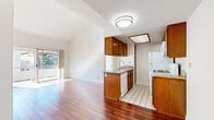 This single-floor residence offers a well-organized layout that balances open communal areas with private living spaces. The open-concept kitchen and living area serves as the heart of the unit, where rich hardwood flooring extends throughout, creating a warm and cohesive aesthetic. The kitchen is outfitted with warm-toned wood cabinetry, granite-style countertops, a peninsula with an undermount sink, and white appliances including a refrigerator, gas range, and dishwasher. Light tile flooring defines the kitchen zone, providing a clean transition from the living area. Vaulted ceilings in the living space amplify the sense of openness, while a sliding glass door leads to a balcony, allowing an abundance of natural light and outdoor views to filter in. The bedrooms are carpeted and well-lit by windows dressed with vertical blinds, with vaulted ceilings in at least one bedroom adding a notable sense of volume. Two full bathrooms are finished with light tile flooring, wood-toned vanity cabinetry, white countertops, and shower-tub combinations enclosed by sliding glass doors. Throughout the unit, neutral wall tones and clean finishes contribute to a bright, move-in-ready atmosphere.