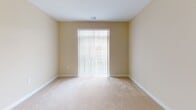 This third-floor unit at 3360 Galena Dr in Frederick, Maryland offers a well-designed single-level layout with a clean, contemporary aesthetic throughout. The kitchen is a standout feature, showcasing rich dark-espresso cabinetry, granite countertops, and a full suite of stainless steel appliances, including a refrigerator, range, and built-in microwave. Light hardwood-style flooring runs through the kitchen and extends into the adjacent living and dining area, which benefits from an open-concept flow. A granite-topped breakfast bar with pendant lighting bridges the kitchen and living space, adding both function and style. Track lighting in the living area provides additional illumination. The bedrooms feature neutral wall tones and plush wall-to-wall carpeting, creating a comfortable atmosphere. One bedroom includes a double-door closet and windows that offer views of the surrounding community. A sliding glass door in another room allows natural light to fill the space and provides access to the outdoors. The bathroom is finished with classic white subway tile surrounding a soaking tub and shower combination, complemented by tile flooring and chrome fixtures. Throughout the unit, warm beige walls and white trim create a cohesive, inviting environment.