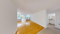 This well-appointed one-bedroom, one-bathroom unit is thoughtfully laid out across a single floor, offering a comfortable and efficient use of space. The living room serves as the centerpiece of the unit, featuring warm, honey-toned parquet hardwood flooring that extends throughout the main living areas. Large floor-to-ceiling windows and a sliding glass door flood the space with abundant natural light while providing green outdoor views, creating a bright and inviting atmosphere. Vertical blinds offer privacy and light control as needed. Baseboard heating units run along the window walls, ensuring year-round comfort.

The bedroom is a well-sized, quiet retreat with its own window overlooking greenery, continuing the parquet flooring, and includes a closet with clean, modern panel doors for convenient storage. White walls throughout the unit contribute to an open, airy feel.

The kitchen features light tile flooring, white cabinetry with ample upper and lower storage, a neutral countertop, a tiled backsplash, and a full-size refrigerator. The bathroom is finished in a clean, white palette with tile flooring, a vanity with a granite-style countertop, a mirrored medicine cabinet, and a full bathtub-shower combination.