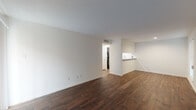 This single-floor residence offers a clean, modern aesthetic throughout its thoughtfully designed layout. The open living area is anchored by rich, dark hardwood-style flooring and crisp white walls, creating a bright and inviting atmosphere. A pass-through counter connects the living space to the kitchen, enhancing the open feel of the common areas. Large vertical blinds allow natural light to filter into the living room.

The galley-style kitchen is well-equipped, featuring dark espresso cabinetry, granite countertops, a stainless steel sink, and black appliances including a refrigerator and range. Ample upper and lower cabinet storage makes this kitchen both functional and visually striking.

The bedrooms are finished with warm, neutral carpet and each include ceiling fans with light fixtures for comfort and airflow. The rooms are generously sized with white panel doors and multiple electrical outlets, providing versatile living options.

The bathroom showcases a standout design element: bold marble-patterned wall surrounds in the tub and shower area, featuring dramatic black veining against a white background, paired with a classic white tub and toilet. The overall layout of the space, as seen in the dollhouse view, is compact yet efficient, making excellent use of every area.