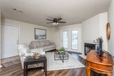 Located at 101 Montrose Ct in Dothan, Alabama, this single-floor home offers a well-organized layout with comfortable living spaces throughout. The living room serves as the heart of the home, anchored by a tile-surround fireplace and complemented by rich hardwood-style flooring, a ceiling fan, and French doors that invite natural light and provide access to the outdoors. The adjacent dining area features a stylish chandelier overhead and ample space for a full dining set, making it ideal for everyday meals or entertaining. The kitchen is outfitted with warm oak cabinetry, dark green countertops, and white appliances including a range, microwave, and refrigerator, along with hardwood-style flooring and a pantry closet for added storage. The bedrooms are carpeted for comfort, with the primary bedroom offering a ceiling fan and generous natural light. The primary bathroom provides a double-sink vanity with oak cabinetry, a large mirror, and hardwood-style flooring. A second full bathroom includes a tub-shower combination, single vanity with oak cabinetry, and matching hardwood-style flooring. Throughout the home, warm neutral walls and consistent flooring choices create a cohesive and inviting atmosphere.