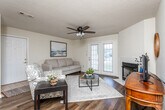 Located at 101 Montrose Ct in Dothan, Alabama, this single-floor home offers a well-organized layout with comfortable living spaces throughout. The living room serves as the heart of the home, anchored by a tile-surround fireplace and complemented by rich hardwood-style flooring, a ceiling fan, and French doors that invite natural light and provide access to the outdoors. The adjacent dining area features a stylish chandelier overhead and ample space for a full dining set, making it ideal for everyday meals or entertaining. The kitchen is outfitted with warm oak cabinetry, dark green countertops, and white appliances including a range, microwave, and refrigerator, along with hardwood-style flooring and a pantry closet for added storage. The bedrooms are carpeted for comfort, with the primary bedroom offering a ceiling fan and generous natural light. The primary bathroom provides a double-sink vanity with oak cabinetry, a large mirror, and hardwood-style flooring. A second full bathroom includes a tub-shower combination, single vanity with oak cabinetry, and matching hardwood-style flooring. Throughout the home, warm neutral walls and consistent flooring choices create a cohesive and inviting atmosphere.
