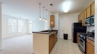 This single-floor residence offers a thoughtfully designed layout that balances functionality and comfort throughout its main living areas. The kitchen serves as a central hub, featuring warm honey-toned cabinetry, dark granite countertops, and a peninsula with pendant lighting overhead. Black and stainless steel appliances — including a gas range, built-in microwave, dishwasher, and refrigerator — complete the space, which is finished with light ceramic tile flooring. The kitchen opens directly to the living area, which is carpeted and receives generous natural light through a sliding glass door that leads to a private balcony.

Two well-sized bedrooms offer plush carpeting, large windows with blinds, and ceiling fans to maintain comfort year-round. The primary bedroom includes a walk-in closet, while a secondary bedroom provides ample space and direct sightlines to the kitchen and living areas. Both bathrooms are finished with white tile surrounds featuring a tan accent border, tub-shower combos, and tile flooring. One bathroom includes a wood-toned vanity with a granite countertop. The overall palette throughout is light and neutral, creating a clean, bright ambiance that maximizes the sense of space.