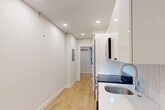 Located at 15 Bartlett Pl in Boston's historic North End neighborhood, this efficiently designed two-bedroom, one-bathroom unit offers a thoughtfully renovated interior with clean, modern finishes throughout. Light hardwood floors run continuously across all rooms, lending warmth and visual cohesion to the space.

The galley-style kitchen is well-appointed with high-gloss white cabinetry, quartz countertops, a decorative hexagonal tile backsplash, and a full suite of stainless steel appliances including a range, built-in microwave, and dishwasher. Recessed lighting illuminates the kitchen and hallway, creating a bright, polished atmosphere.

Both bedrooms feature neutral walls, hardwood floors, and individual wall-mounted mini-split HVAC units for independent climate control. The primary bedroom includes two windows overlooking neighboring brick facades, bringing in natural light, and is complemented by a built-in wardrobe. The second bedroom is a cozy, quiet space with its own window and mini-split unit.

The bathroom showcases a clean, contemporary design with large-format white subway tile in the walk-in shower, a mosaic penny-tile shower floor, a compact dark-vanity with an integrated sink, and a framed mirror. The overall aesthetic throughout is crisp, modern, and move-in ready.
