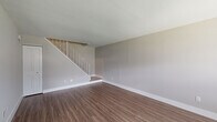 This two-bedroom, one-bathroom two-story home offers a thoughtfully designed layout spread across two well-proportioned floors. The main level features a welcoming entryway with a front door accented by a transom window, allowing natural light to fill the open living area. Durable hardwood-style flooring runs throughout the ground floor, complementing the neutral gray walls and clean white trim. A staircase with a white metal balustrade and wood-toned steps connects the two levels, serving as a functional architectural focal point.

The kitchen is a standout feature, boasting modern two-toned cabinetry with glossy white uppers and wood-grain lower cabinets, crisp white countertops, a striking blue-gray subway tile backsplash, and a full suite of stainless steel appliances including a range, microwave, dishwasher, and refrigerator.

Upstairs, both bedrooms are finished with plush wall-to-wall carpeting and feature windows that bring in natural light. The primary bedroom offers generous proportions and includes a dedicated closet. The bathroom is efficiently designed and incorporates a stacked washer and dryer unit, dark-toned floor tiles, a white vanity with modern fixtures, and a mirrored medicine cabinet for added storage.