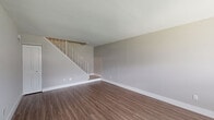 This two-bedroom, one-bathroom two-story home offers a thoughtfully designed layout spread across two well-proportioned floors. The main level features a welcoming entryway with a front door accented by a transom window, allowing natural light to fill the open living area. Durable hardwood-style flooring runs throughout the ground floor, complementing the neutral gray walls and clean white trim. A staircase with a white metal balustrade and wood-toned steps connects the two levels, serving as a functional architectural focal point.

The kitchen is a standout feature, boasting modern two-toned cabinetry with glossy white uppers and wood-grain lower cabinets, crisp white countertops, a striking blue-gray subway tile backsplash, and a full suite of stainless steel appliances including a range, microwave, dishwasher, and refrigerator.

Upstairs, both bedrooms are finished with plush wall-to-wall carpeting and feature windows that bring in natural light. The primary bedroom offers generous proportions and includes a dedicated closet. The bathroom is efficiently designed and incorporates a stacked washer and dryer unit, dark-toned floor tiles, a white vanity with modern fixtures, and a mirrored medicine cabinet for added storage.