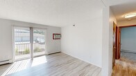Located at 618 W Bridge St in Owatonna, Minnesota, this two-bedroom, one-bathroom unit offers a well-organized single-floor layout designed for comfortable everyday living. The living room is a bright, open space featuring light wood-style flooring, a sliding glass door that leads to a private balcony, a wall-mounted air conditioning unit, and a baseboard heating system. Natural light flows generously through the large glass door, creating a welcoming atmosphere. The kitchen is a standout feature, showcasing dark grey cabinetry, granite countertops, a stainless steel range, dishwasher, and a double-basin sink with a modern gooseneck faucet — a well-appointed space for cooking and entertaining. The primary bedroom is spacious and includes an open closet with built-in shelving, plush carpeting, a ceiling fan, and baseboard heating. The second bedroom offers similar comfort with carpeted floors, a ceiling fan, a window with natural light, and baseboard heating. The bathroom is neatly finished with granite countertops, dark wood cabinetry, a large mirror, and a shower-tub combination. Throughout the unit, a neutral color palette and clean finishes contribute to a bright, functional, and move-in-ready living environment.
