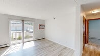 Located at 618 W Bridge St in Owatonna, Minnesota, this two-bedroom, one-bathroom unit offers a well-organized single-floor layout designed for comfortable everyday living. The living room is a bright, open space featuring light wood-style flooring, a sliding glass door that leads to a private balcony, a wall-mounted air conditioning unit, and a baseboard heating system. Natural light flows generously through the large glass door, creating a welcoming atmosphere. The kitchen is a standout feature, showcasing dark grey cabinetry, granite countertops, a stainless steel range, dishwasher, and a double-basin sink with a modern gooseneck faucet — a well-appointed space for cooking and entertaining. The primary bedroom is spacious and includes an open closet with built-in shelving, plush carpeting, a ceiling fan, and baseboard heating. The second bedroom offers similar comfort with carpeted floors, a ceiling fan, a window with natural light, and baseboard heating. The bathroom is neatly finished with granite countertops, dark wood cabinetry, a large mirror, and a shower-tub combination. Throughout the unit, a neutral color palette and clean finishes contribute to a bright, functional, and move-in-ready living environment.