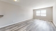 Located in Columbus, OH (43229), this single-floor unit offers a clean, modern aesthetic throughout. The open living area is finished with light gray luxury vinyl plank flooring that extends through the main spaces, creating a cohesive and contemporary look. Neutral gray walls and white trim contribute to a bright, airy atmosphere, while a window allows natural light to fill the room.

The kitchen is well-appointed with white shaker-style cabinetry, granite-look countertops, and stainless steel appliances including a Samsung gas range. A built-in range hood and ample upper and lower cabinet storage make this a highly functional cooking space.

The bedrooms feature plush carpeting in warm neutral tones, with multiple windows allowing generous natural light. One bedroom includes a built-in overhead shelf, adding practical storage. Additional closet space is accessible throughout the unit.

The bathroom is neatly finished with gray vinyl plank flooring, a white vanity with clean hardware, a full tub-shower combination, and neutral wall tones that create a calm, utilitarian space.

A dedicated hallway connects the living, sleeping, and bathroom areas, with visible HVAC venting indicating climate control throughout. The floorplan, as seen in the dollhouse view, is efficiently laid out to maximize usable space across all areas.