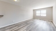 Located in Columbus, OH (43229), this single-floor unit offers a clean, modern aesthetic throughout. The open living area is finished with light gray luxury vinyl plank flooring that extends through the main spaces, creating a cohesive and contemporary look. Neutral gray walls and white trim contribute to a bright, airy atmosphere, while a window allows natural light to fill the room.

The kitchen is well-appointed with white shaker-style cabinetry, granite-look countertops, and stainless steel appliances including a Samsung gas range. A built-in range hood and ample upper and lower cabinet storage make this a highly functional cooking space.

The bedrooms feature plush carpeting in warm neutral tones, with multiple windows allowing generous natural light. One bedroom includes a built-in overhead shelf, adding practical storage. Additional closet space is accessible throughout the unit.

The bathroom is neatly finished with gray vinyl plank flooring, a white vanity with clean hardware, a full tub-shower combination, and neutral wall tones that create a calm, utilitarian space.

A dedicated hallway connects the living, sleeping, and bathroom areas, with visible HVAC venting indicating climate control throughout. The floorplan, as seen in the dollhouse view, is efficiently laid out to maximize usable space across all areas.