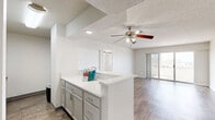 Located in the heart of downtown Oklahoma City, this one-bedroom, three-bathroom unit offers a well-organized, single-floor layout designed for efficient urban living. The open-concept living and dining area is finished with wood-look plank flooring, a ceiling fan, and a textured ceiling. Sliding glass doors lead directly to a private patio, filling the space with natural light and offering views of the Oklahoma City skyline.

The kitchen is thoughtfully appointed with white shaker-style cabinetry, white quartz countertops, a classic subway tile backsplash, a stainless steel sink with a modern spring-neck faucet, and black appliances including a range and refrigerator. A peninsula with gray cabinetry and additional counter space connects the kitchen to the living area.

The bedroom features plush carpeting, a ceiling fan, and a large window framing impressive city skyline views, along with access to a closet. The bathrooms are cleanly finished with white tile, quartz vanity surfaces, and wood-look flooring. Three closets throughout the unit provide ample storage. The unit's neutral color palette and updated finishes create a bright, move-in-ready atmosphere in a prime urban location.